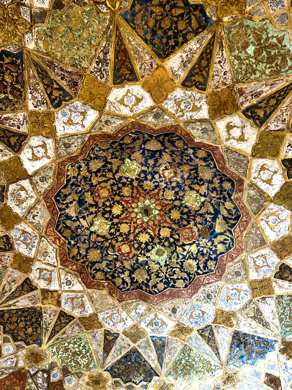 El techo pintado y dorado del interior de la Tumba de Itimad-ud-Daulah: una estrella de motivos florales en oro, azul y verde