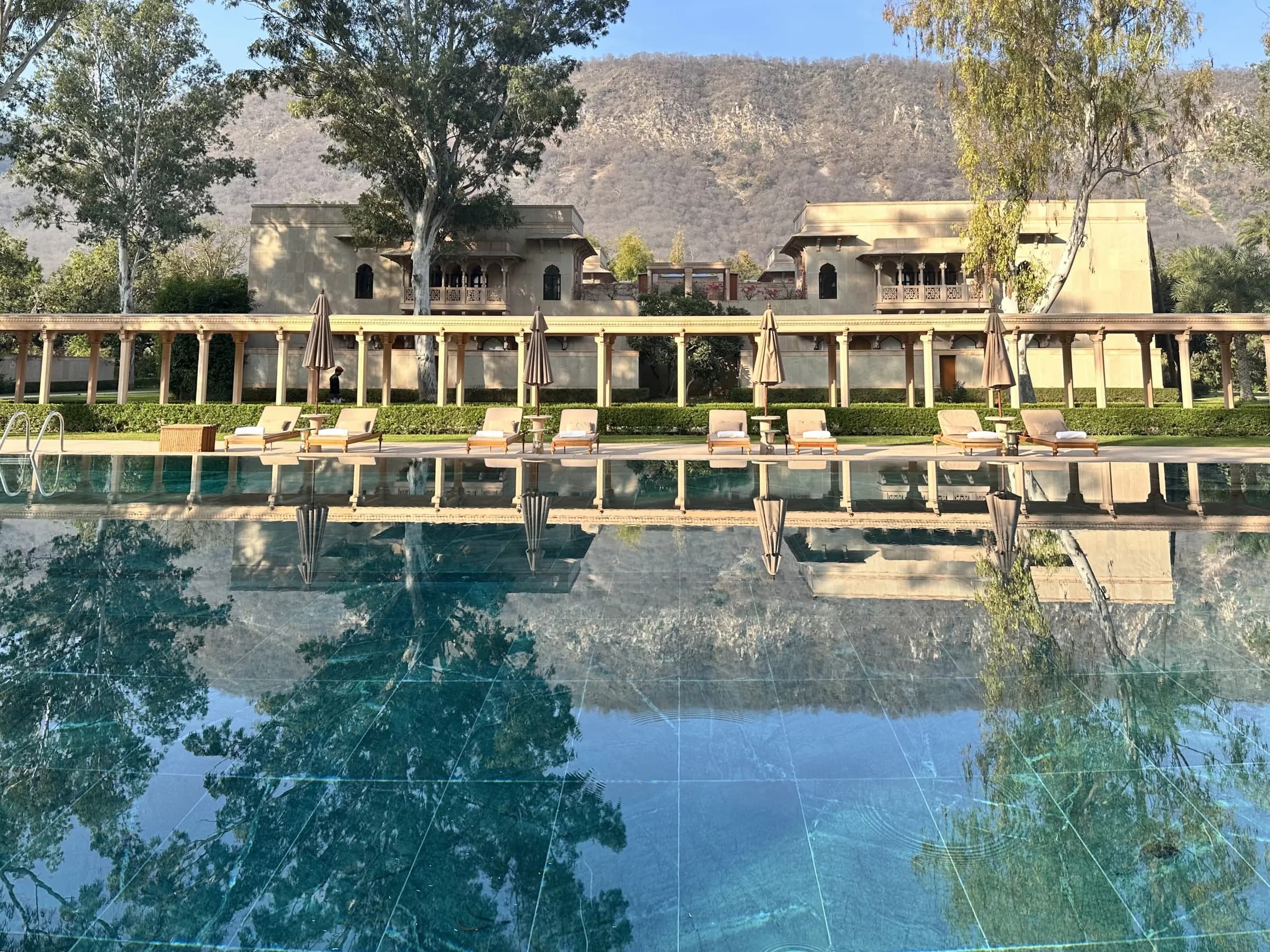 La larga piscina de mármol verde de Amanbagh, que refleja la columnata, los pabellones de arenisca y las colinas Aravalli en una mañana despejada