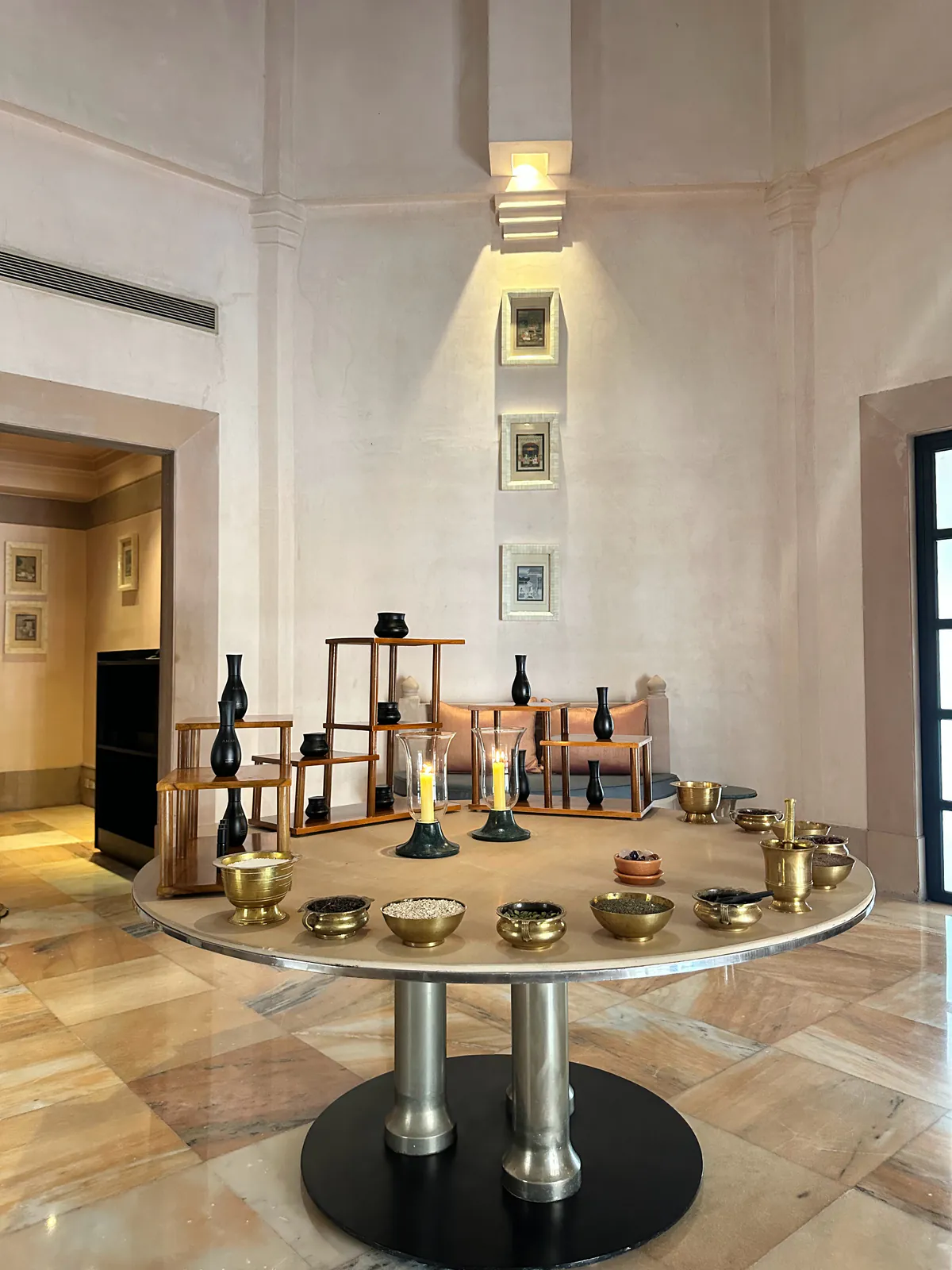 Cuencos de latón y jarrones oscuros sobre una mesa redonda en el Aman Spa de Amanbagh