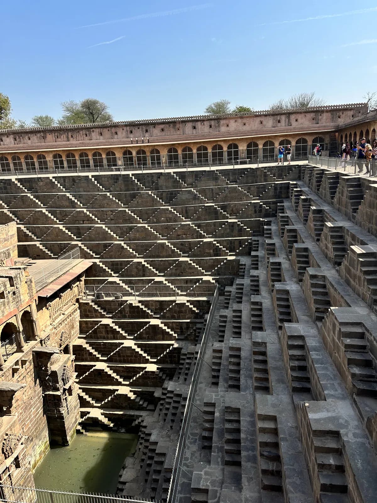 Los tramos de escalones entrecruzados del pozo escalonado de Chand Baori, en Abhaneri, que descienden hasta el agua verde