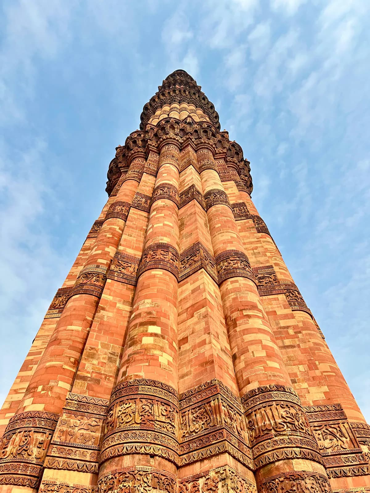 El fuste acanalado de arenisca roja del Qutub Minar contra un cielo azul, visto desde su base