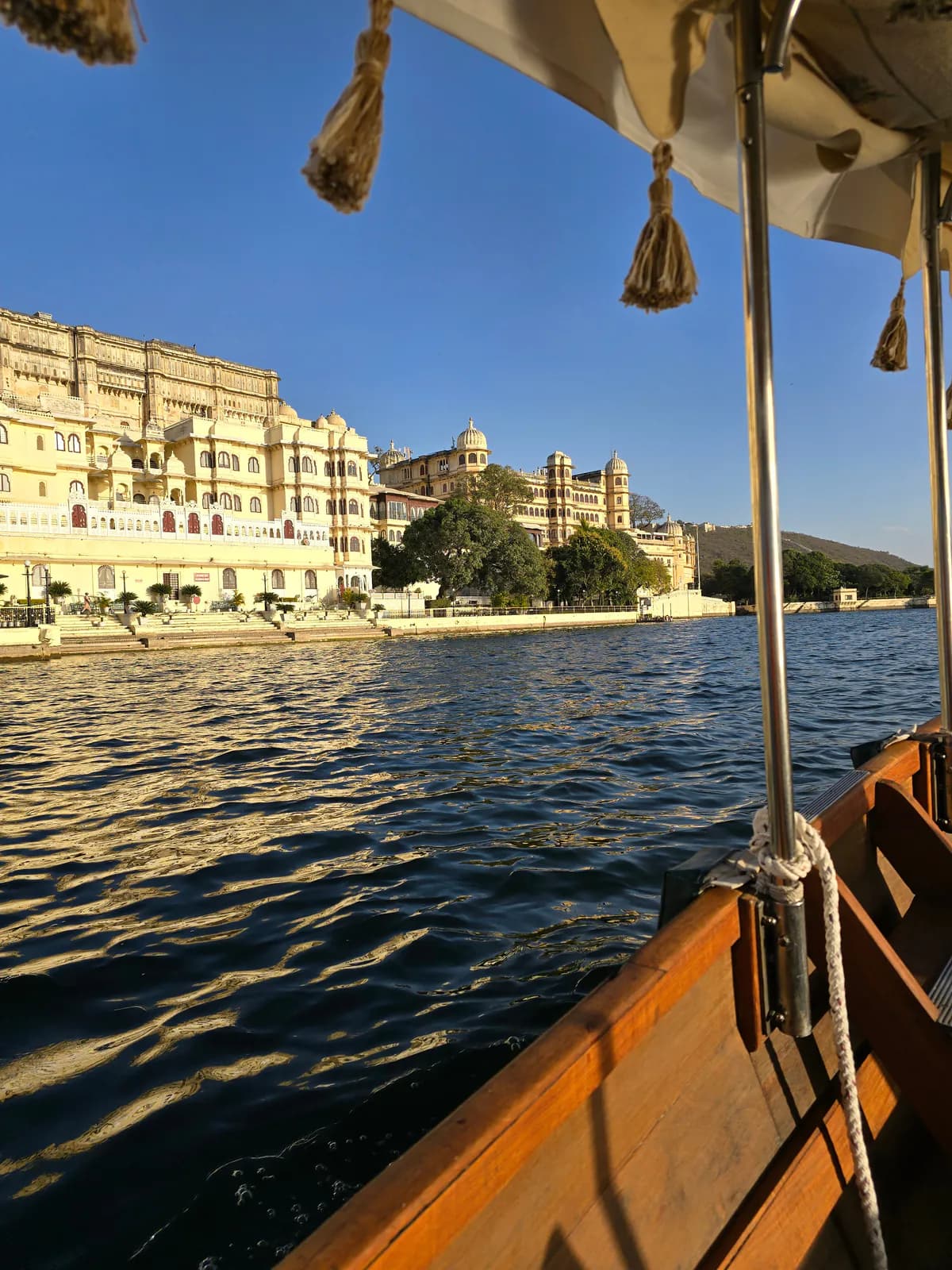 El Palacio de la Ciudad de Udaipur a orillas del lago Pichola, visto desde una barca bajo un toldo con borlas