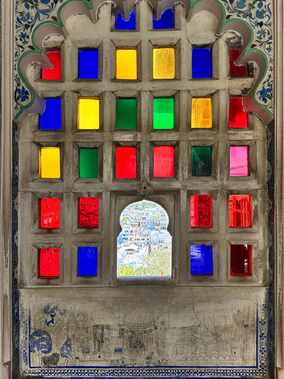 Una ventana de cristales de colores rojo, azul, verde y amarillo en el interior del Palacio de la Ciudad de Udaipur