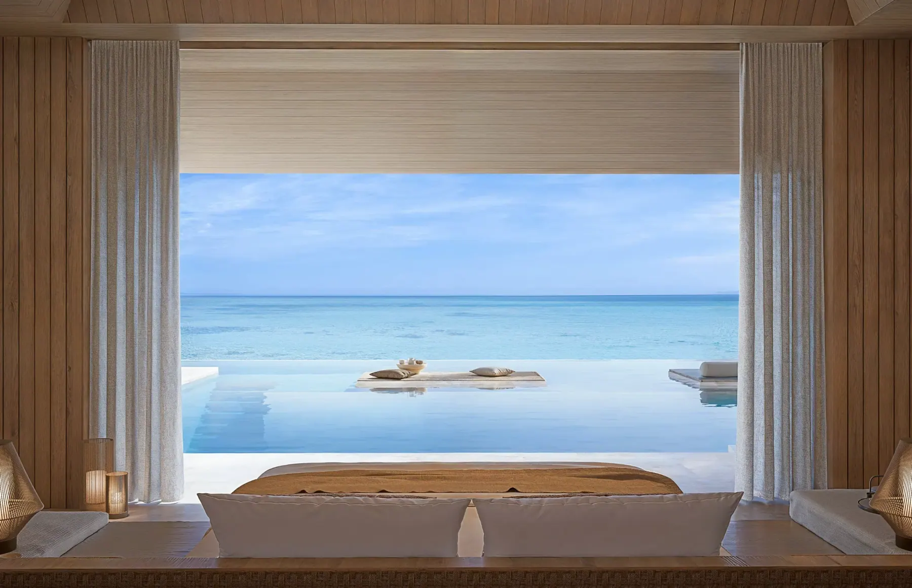 A bedroom opening onto its private infinity pool and the lagoon at Aman Residences, Maldives, in the developer's rendering.