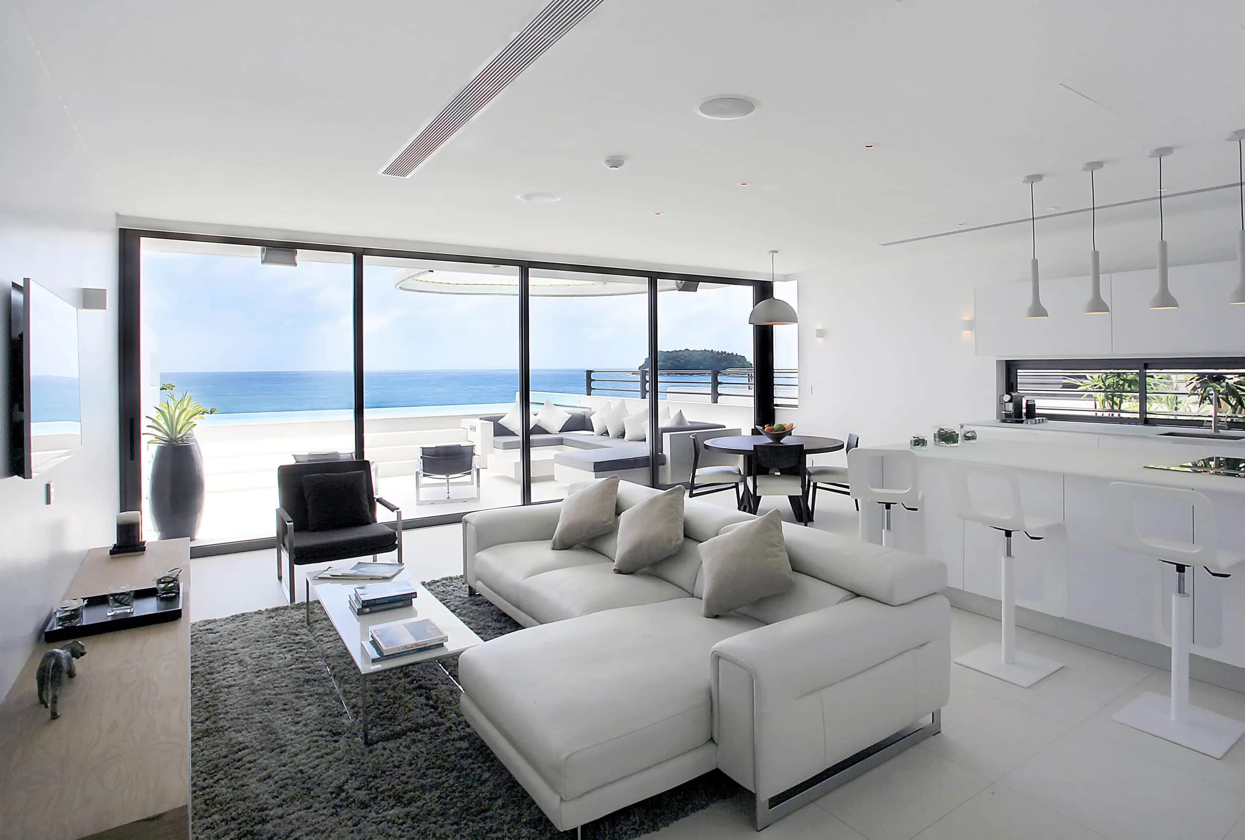 Open-plan living room and kitchen of a Kata Rocks one-bedroom Sky Villa, infinity pool and sea beyond