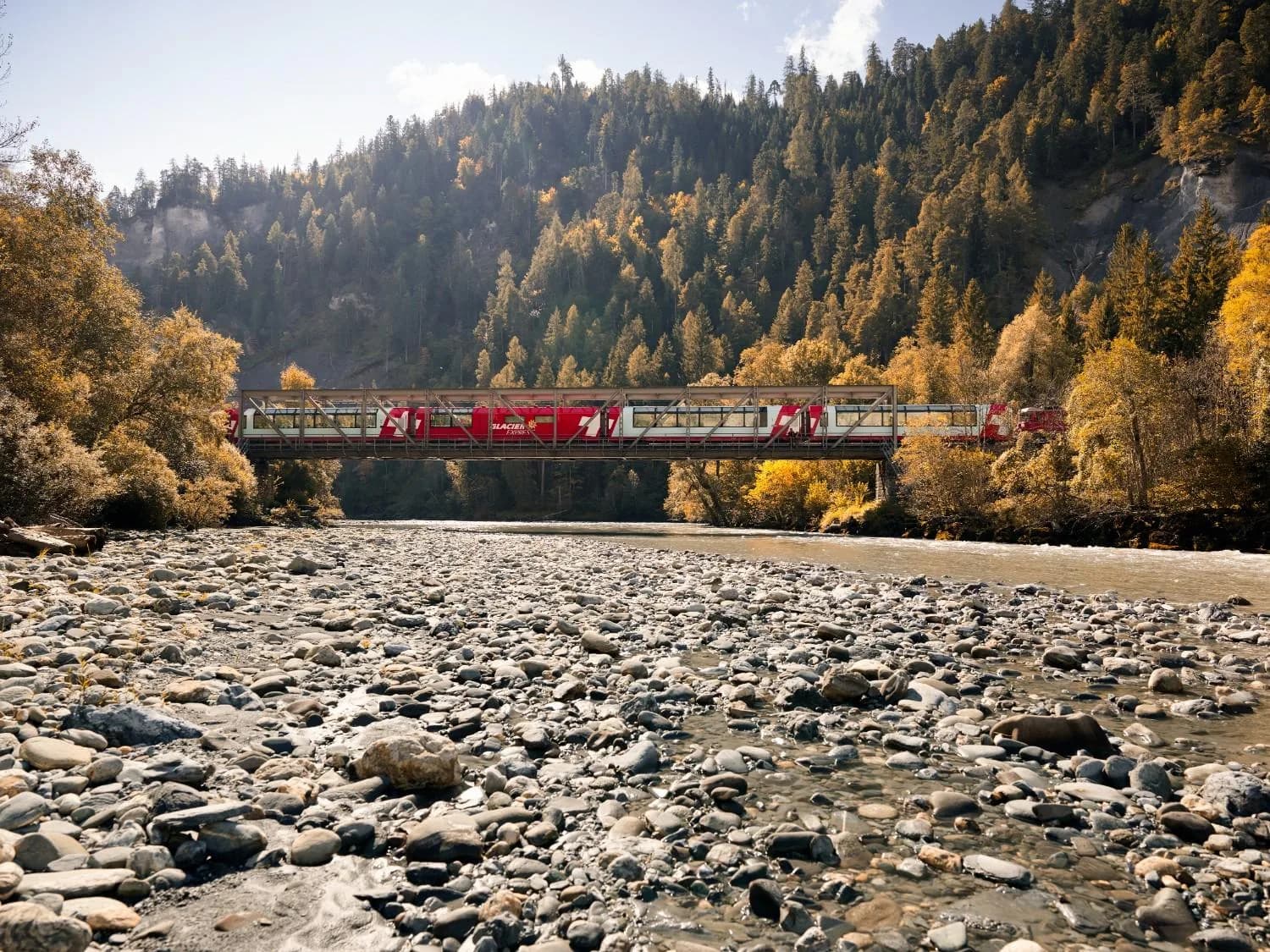 The Glacier Express on a river bridge in autumn