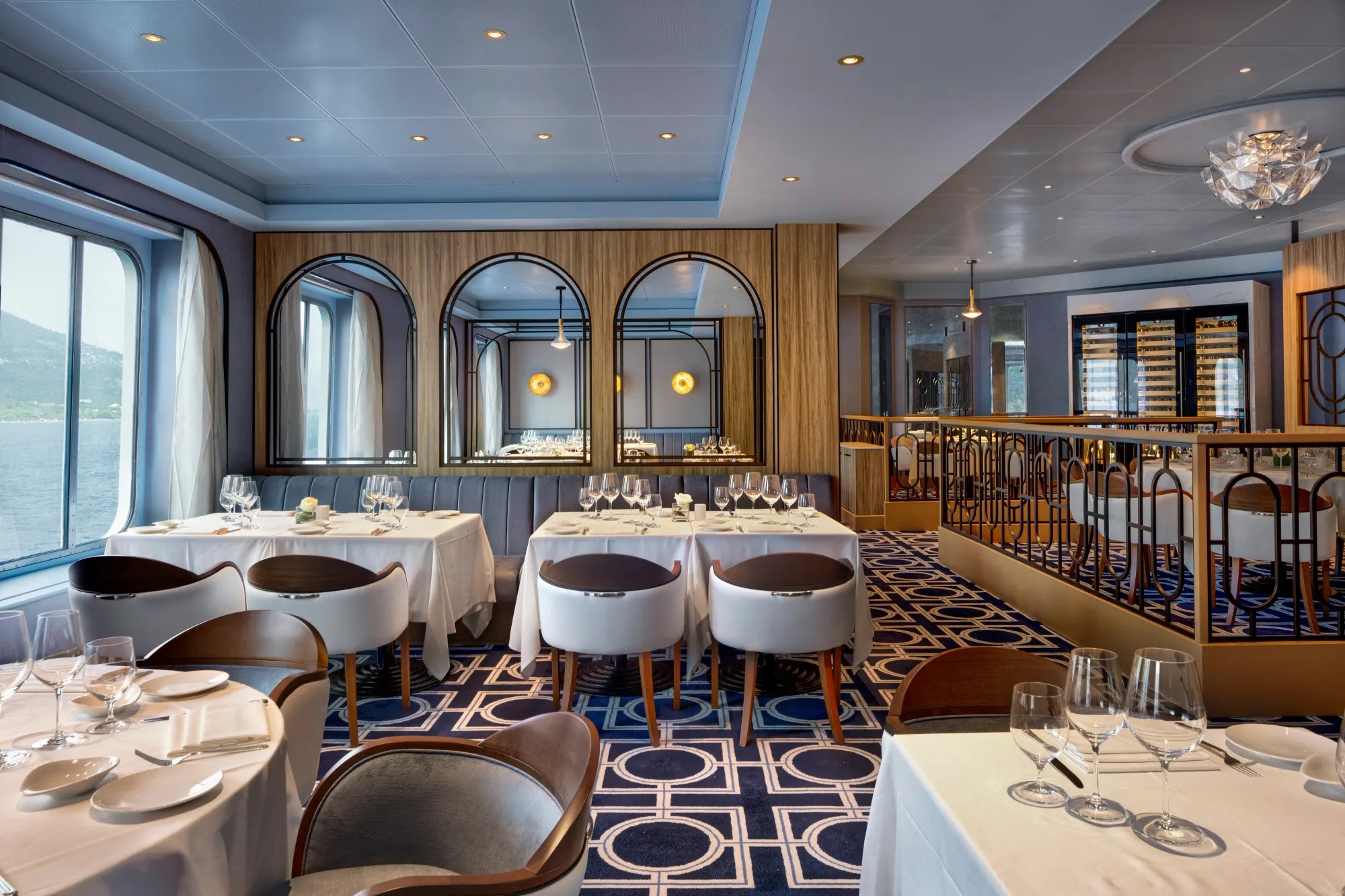 Osteria d'Ovidio on Crystal Symphony, white-clothed tables under arched mirrors, the coast through the window