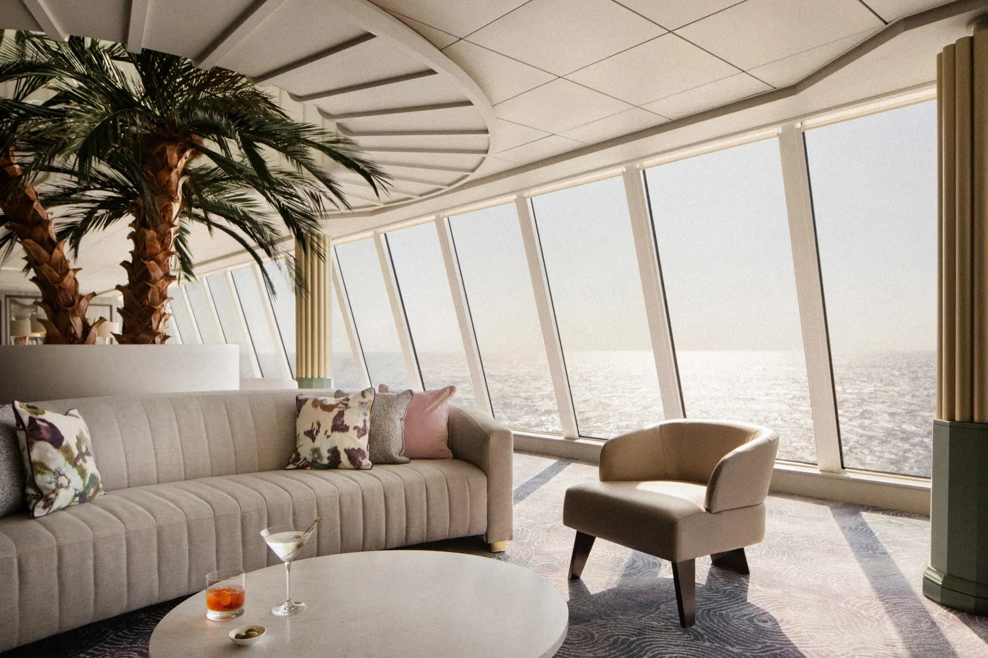 The Palm Court lounge on Crystal Serenity, sofas facing a wall of forward-raked windows over the sea