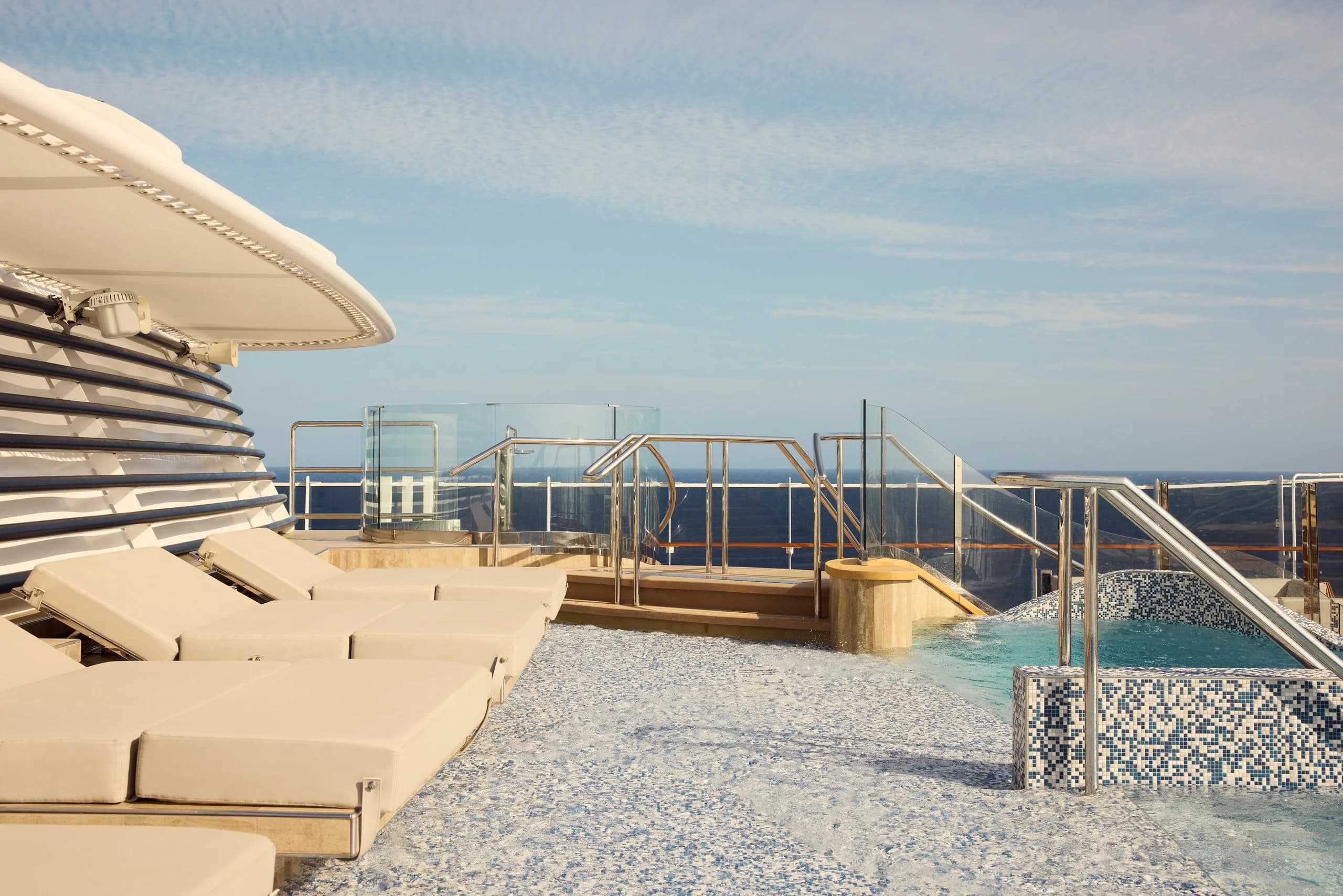 The Helios pool aboard an Explora Journeys ship, mosaic-tiled with loungers facing the sea