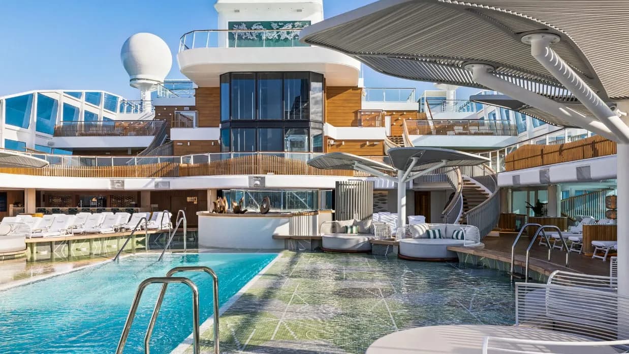The pool deck on Oceania Vista, loungers and shaded daybeds around the pool under the ship's superstructure