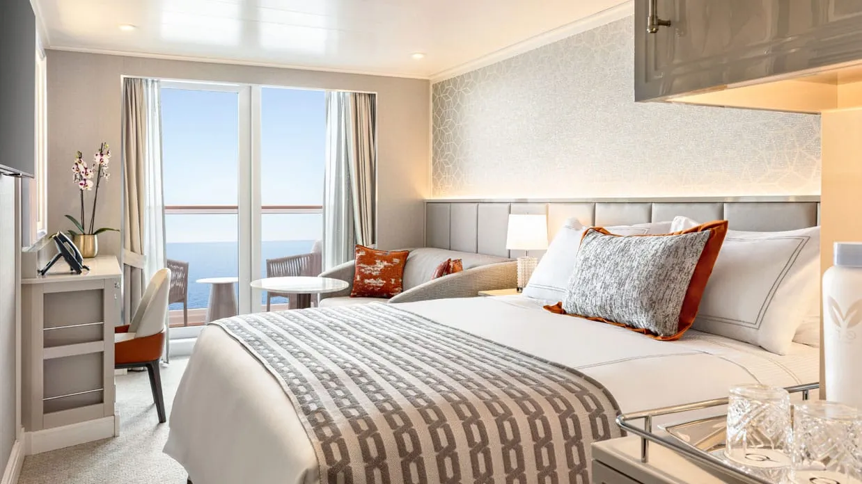A Veranda Stateroom on Oceania Vista, the bed facing glass doors that open onto a veranda over the sea