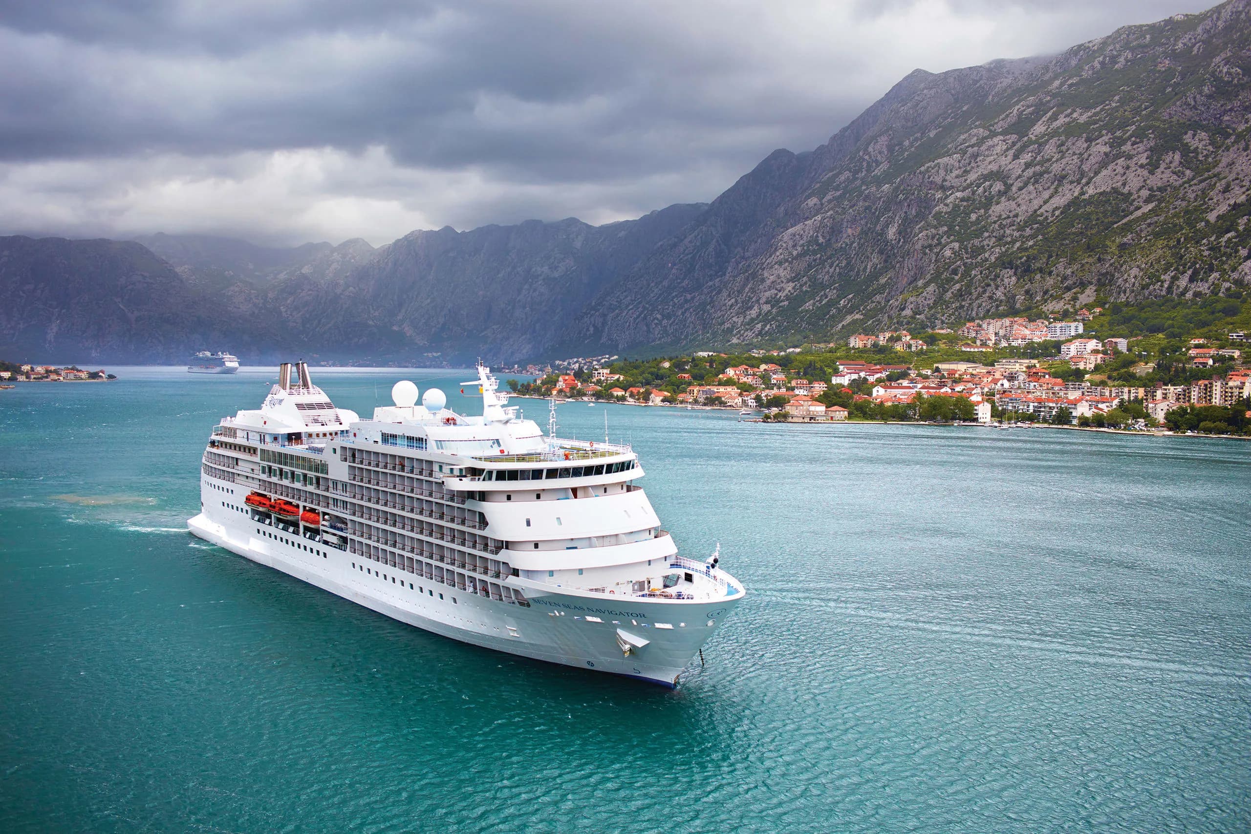 Seven Seas Navigator, a Regent ship, under way in the Bay of Kotor beneath the mountains, a town along the shore