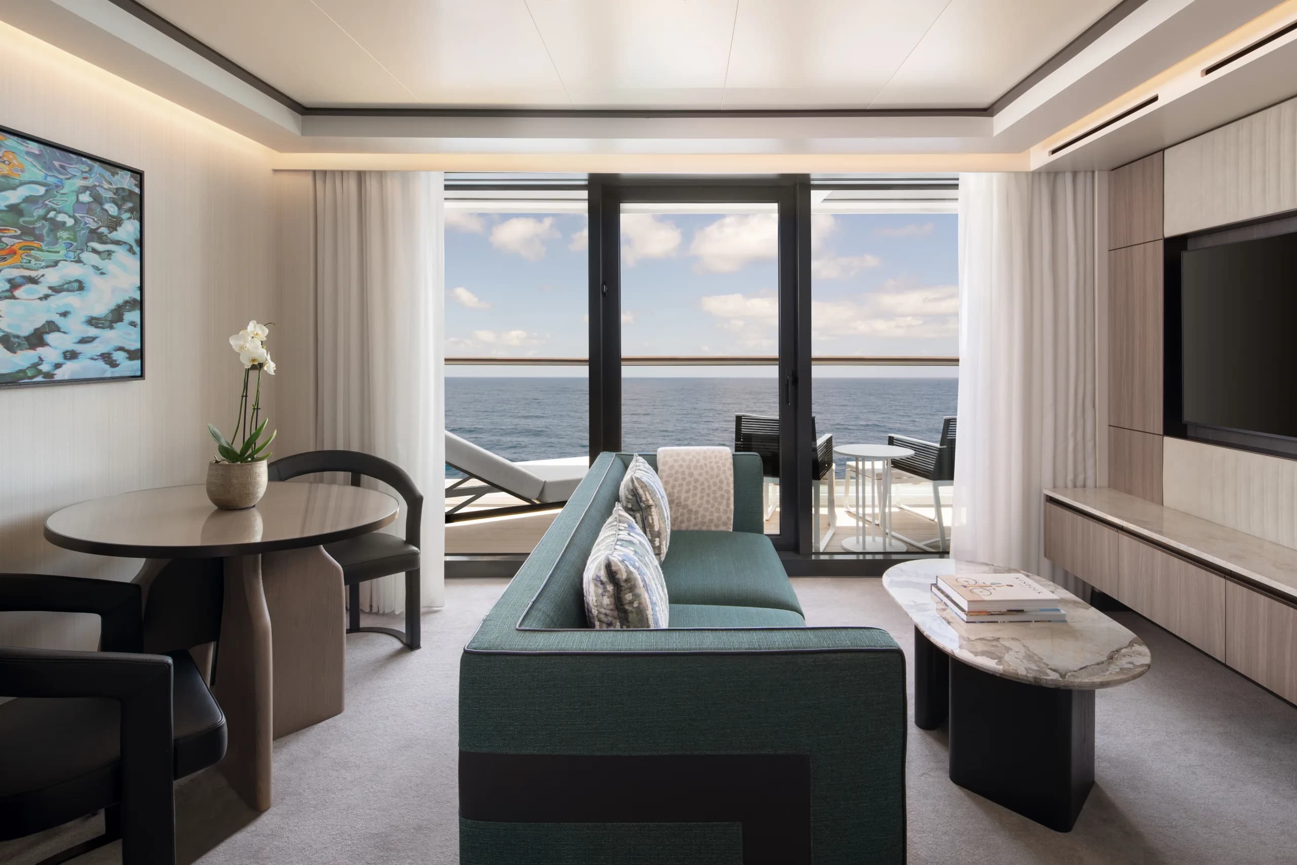A Signature Suite aboard Ilma, with a dining table, a separate seating area and the terrace beyond