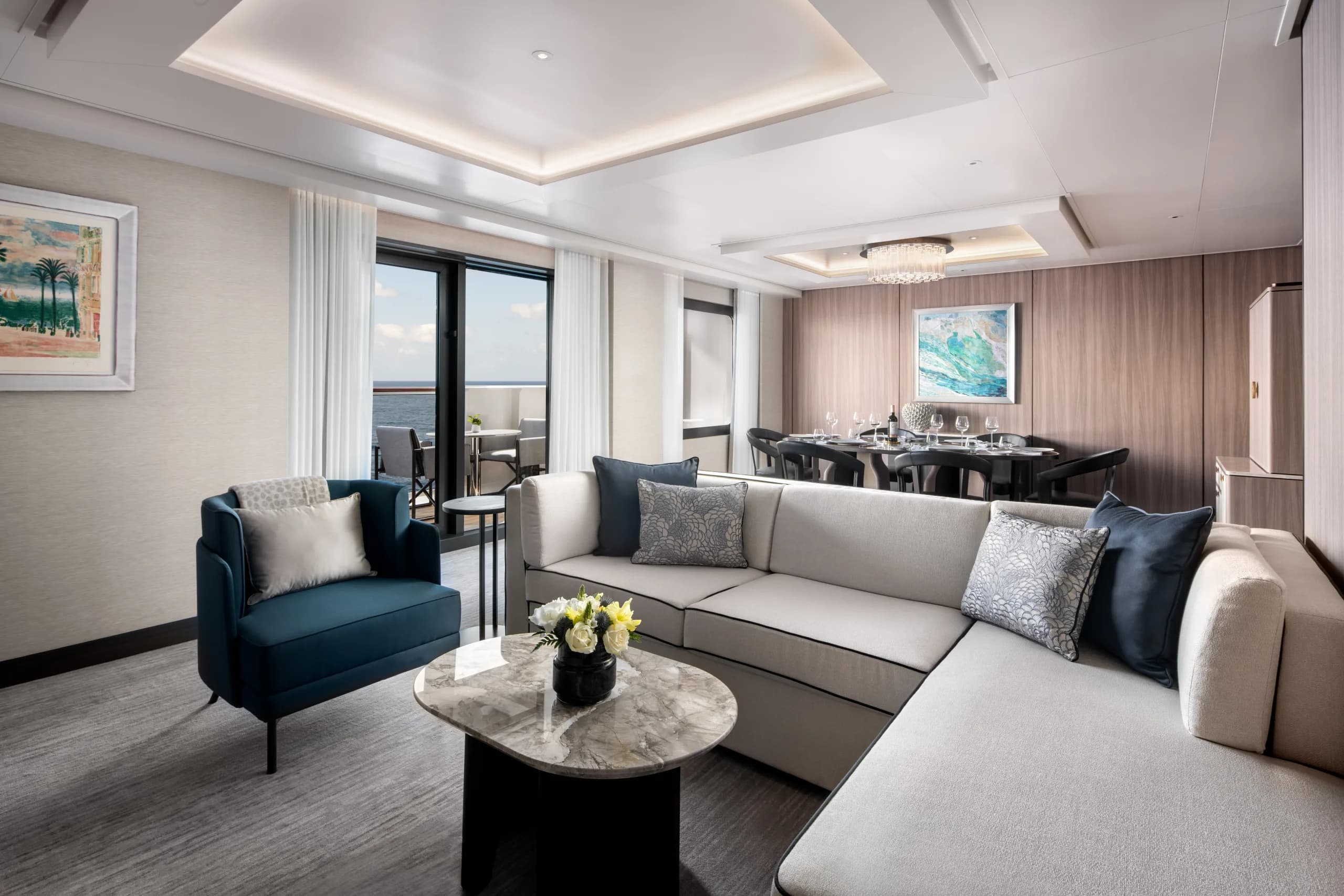 A View Suite aboard Ilma, a long sofa and dining table set against floor-to-ceiling windows
