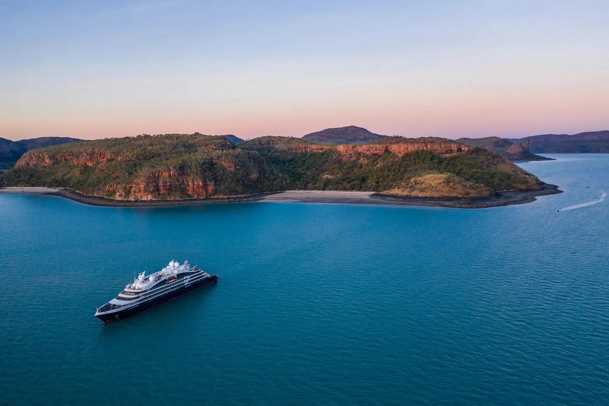 Le Lapérouse at sea off a red-cliffed island on the Kimberley coast of Australia at dusk, seen from the air