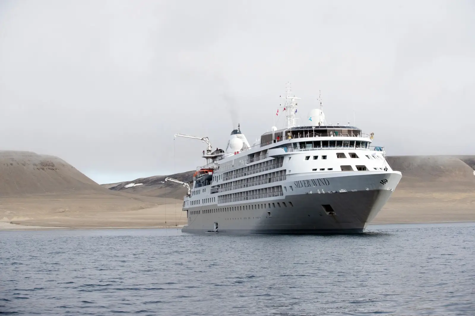 Silver Wind at anchor off a bare, sandy coast under a grey sky