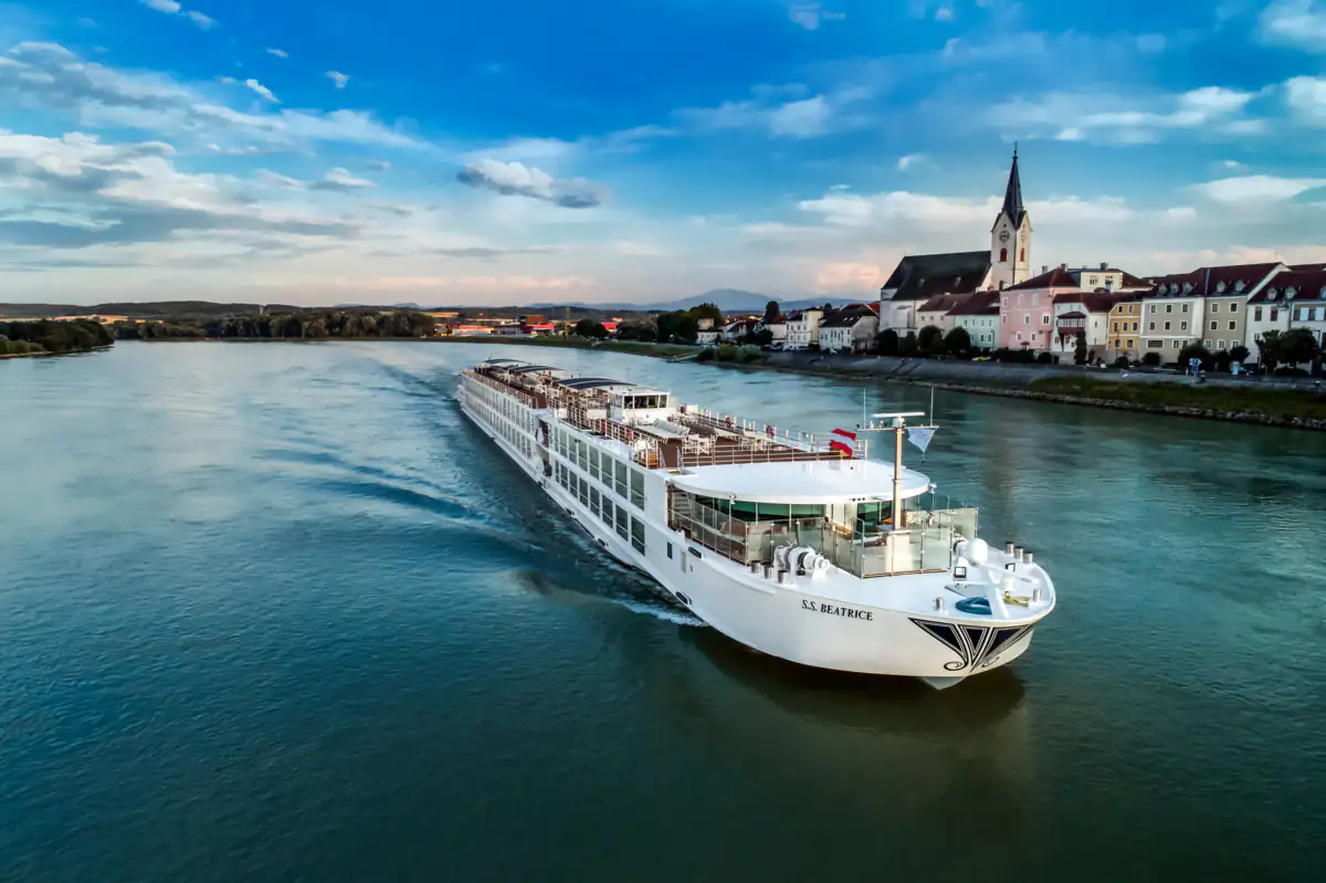 S.S. Beatrice under way, a riverside town and church spire behind