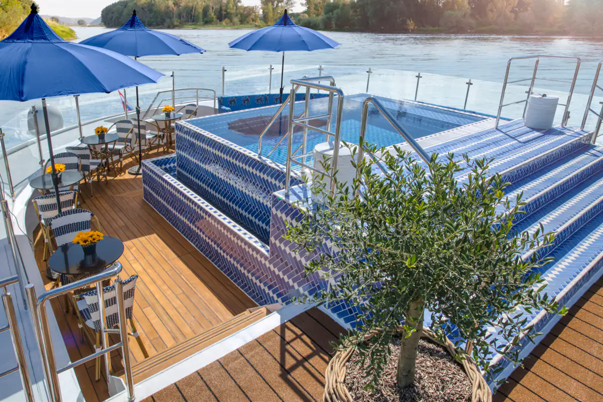 The infinity pool on the Soleil Deck of S.S. Bon Voyage, blue tiles and umbrellas above the river