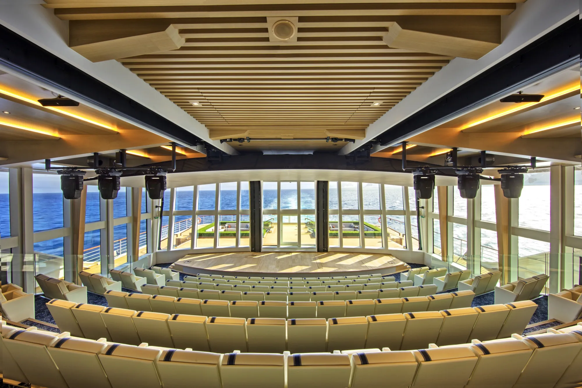 The Aula auditorium, tiered seats facing a stage backed by windows onto the sea