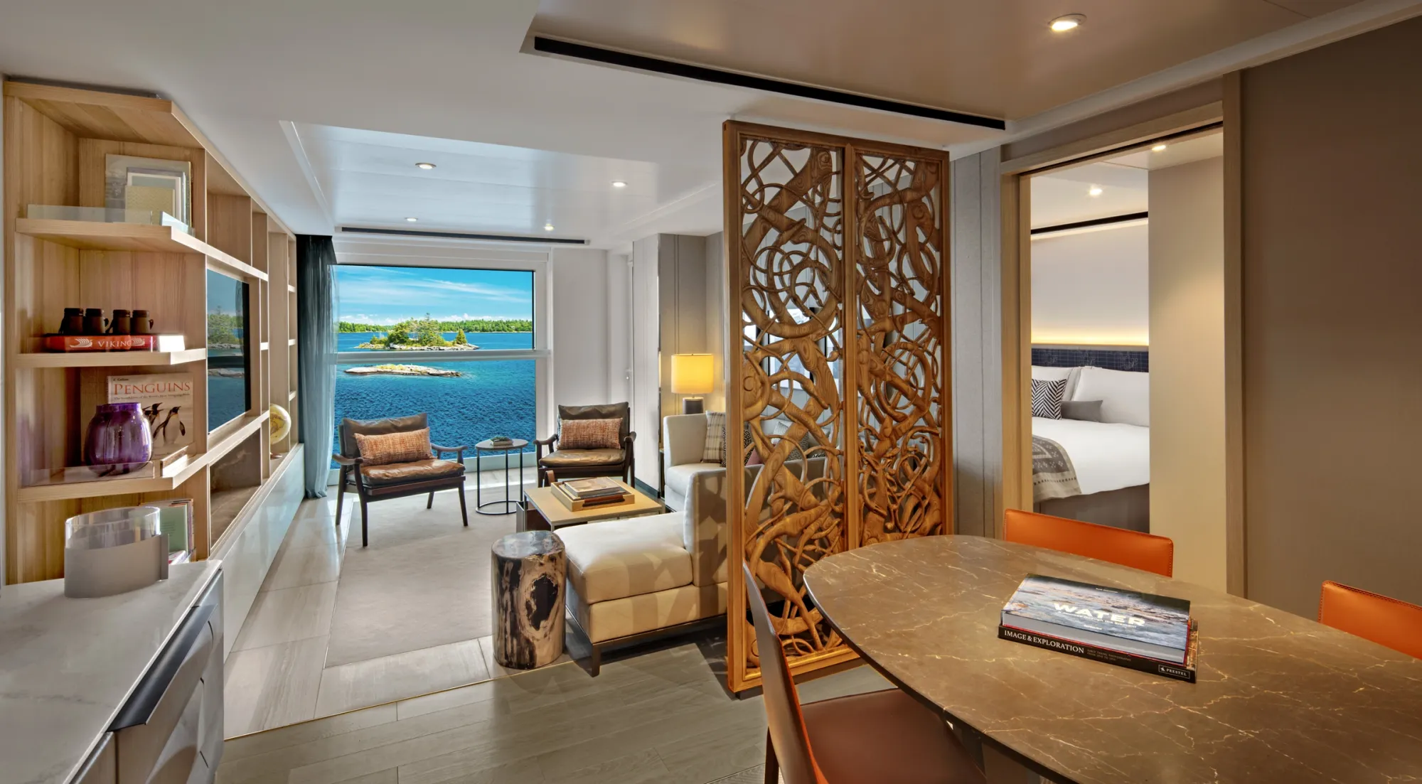 The living and dining room of an Explorer Suite on Viking Octantis, a carved wooden screen and a window over blue water
