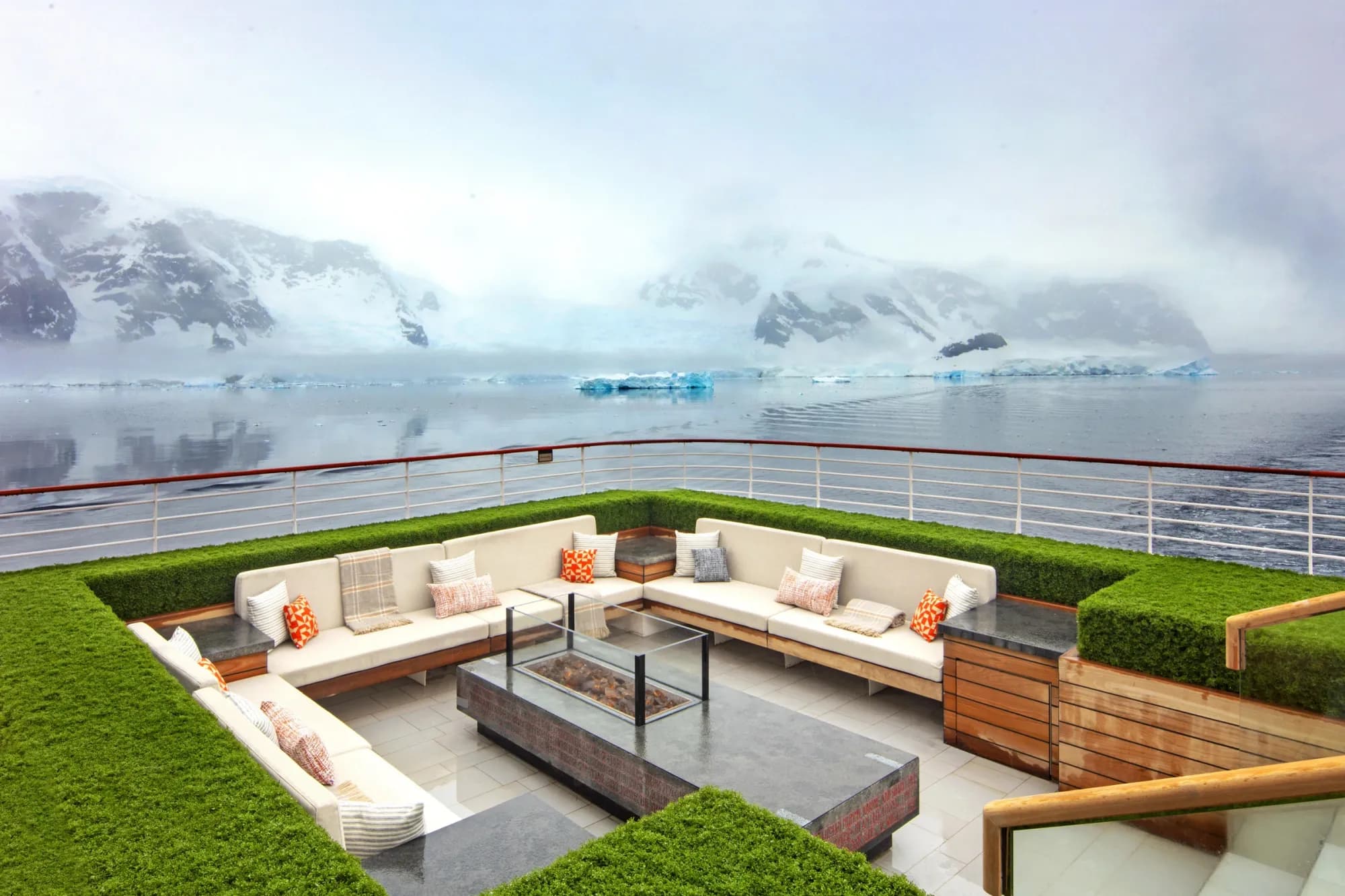 The Finse Terrace, sofas around a glass-walled fire table looking over still water, ice and snowy mountains