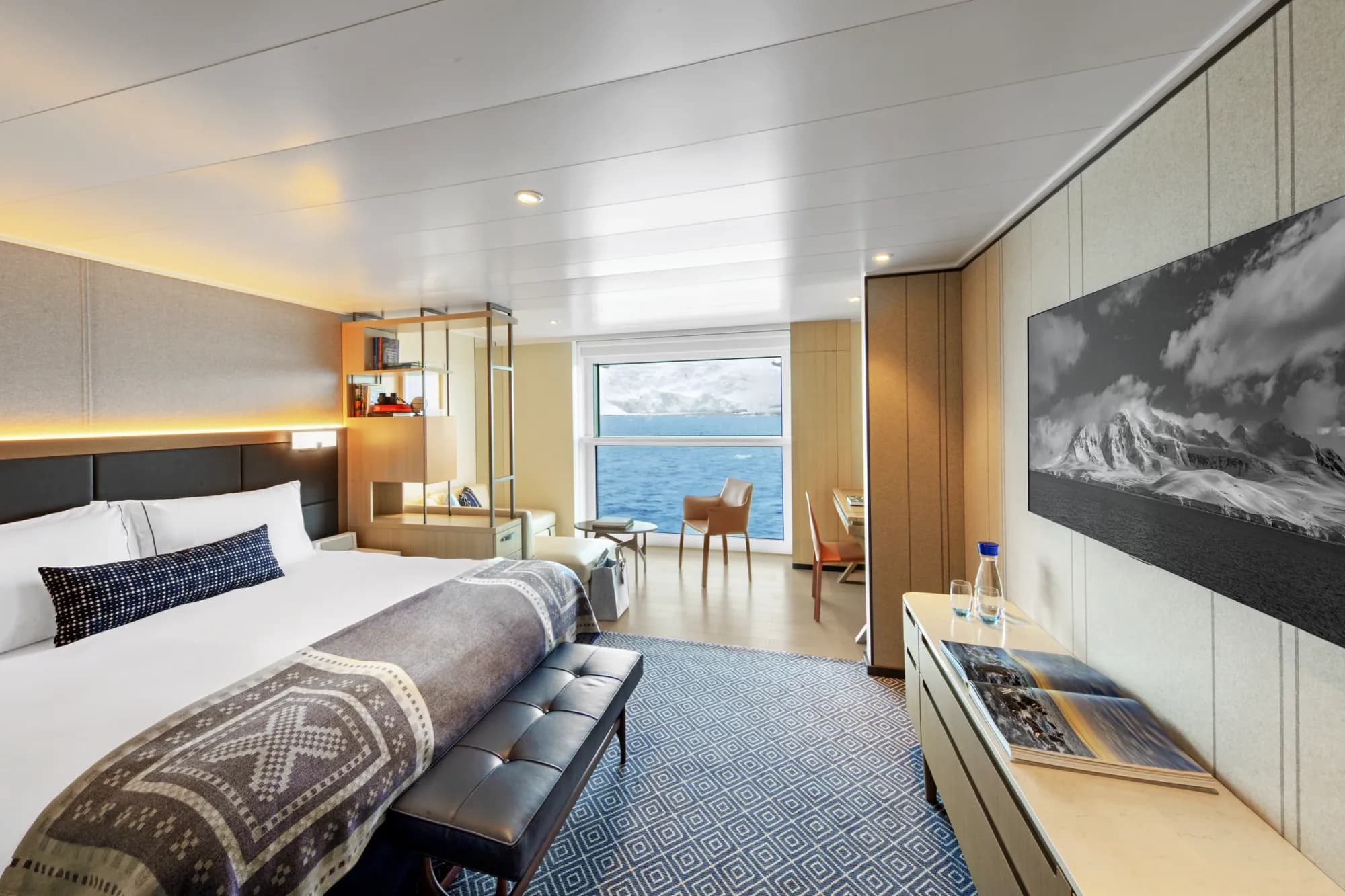 A Nordic Junior Suite on Viking Octantis, a king bed and a seating area by the floor-to-ceiling Nordic Balcony window over the sea