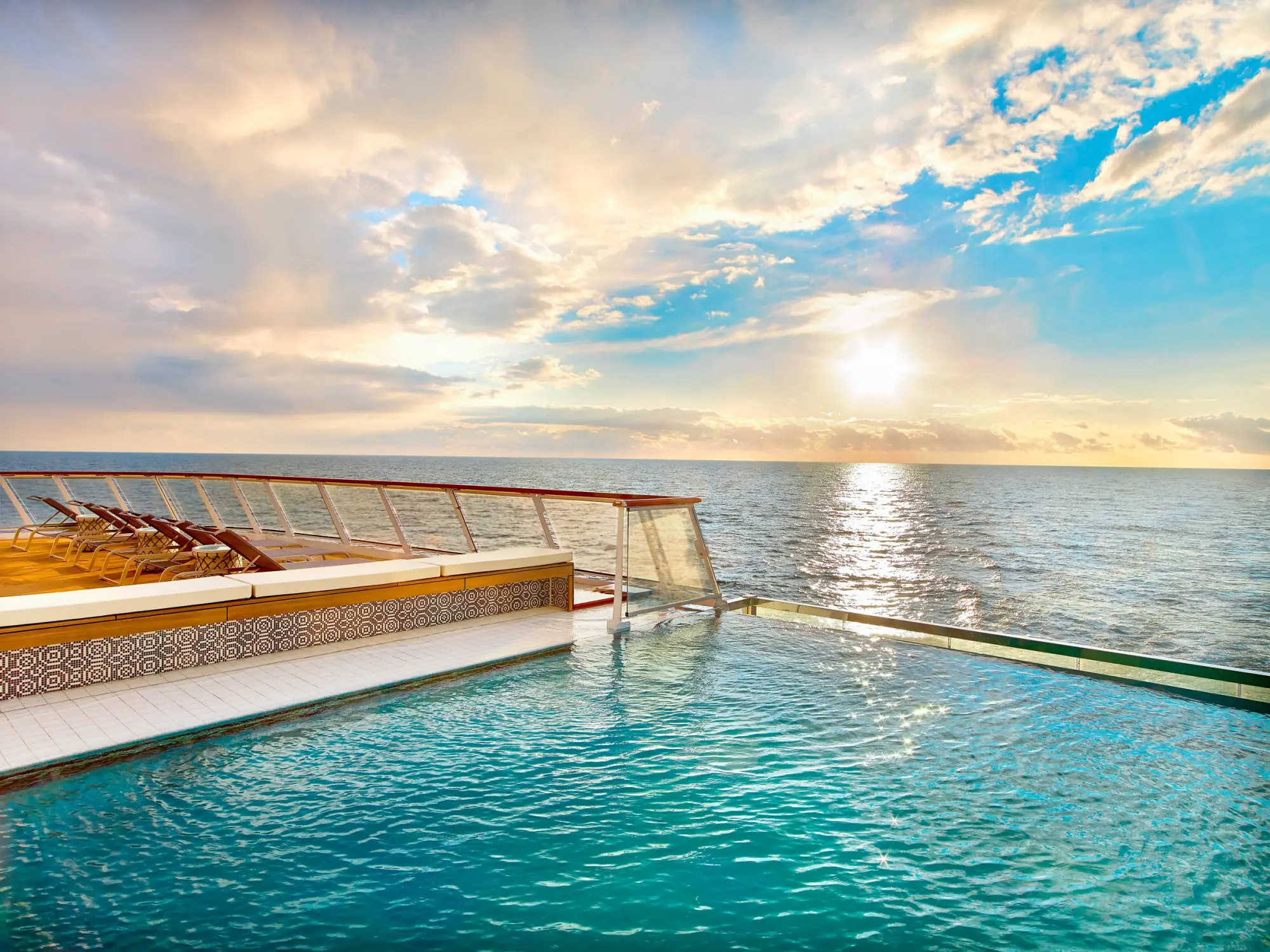 The infinity pool at the stern of a Viking ocean ship, its glass edge meeting the open sea at sunset