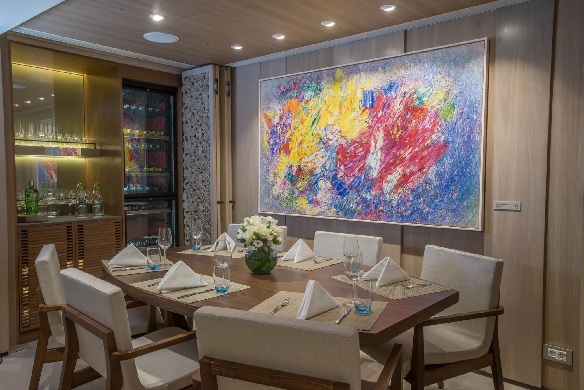 The dining room of a Viking Owner's Suite, a table for eight below a large abstract painting