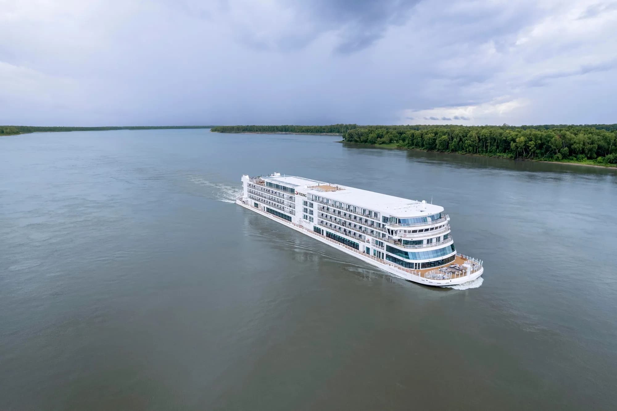 Viking Mississippi under way on a broad river between forested banks