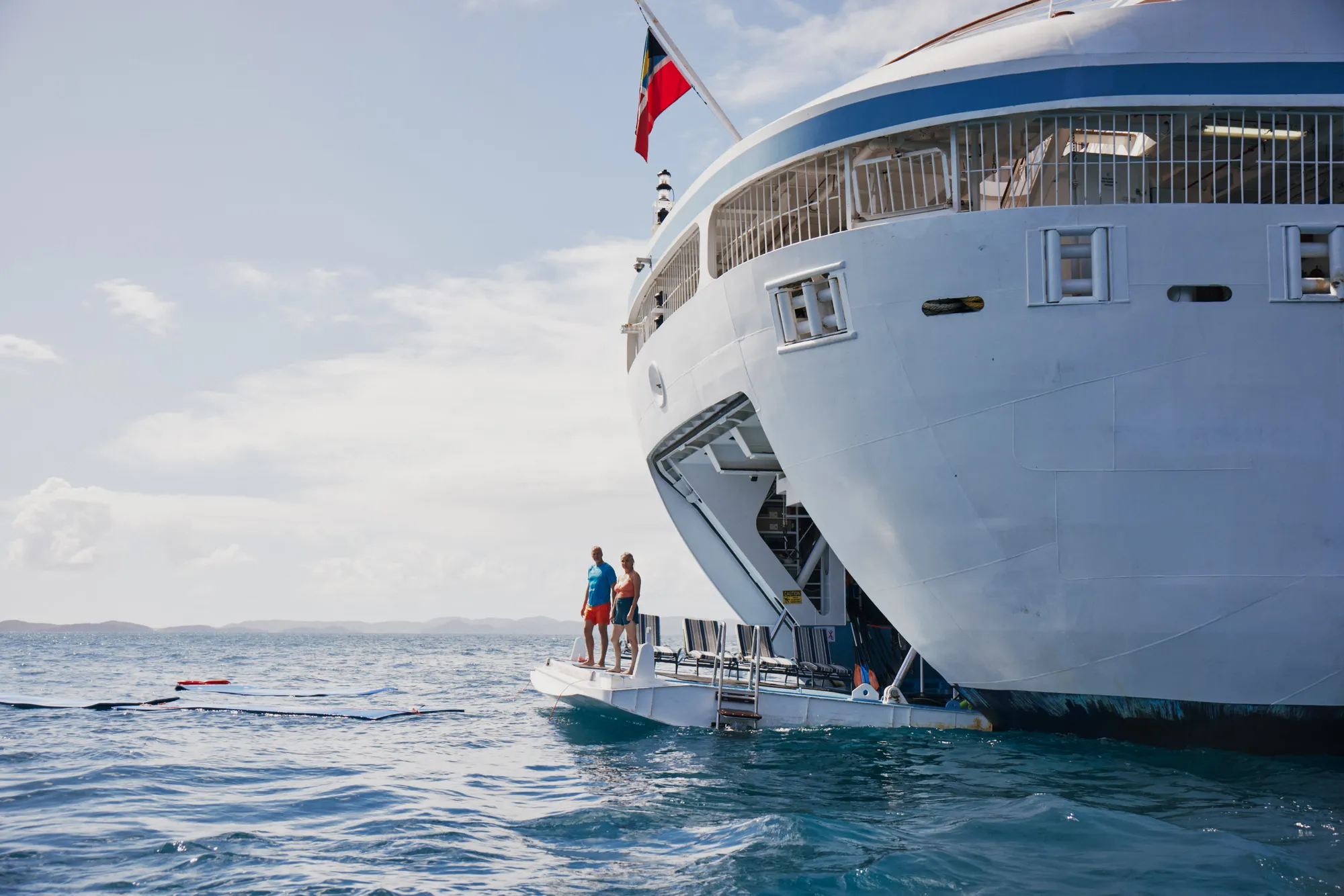 The stern watersports platform lowered at anchor, floating mats in the water and two guests on the platform