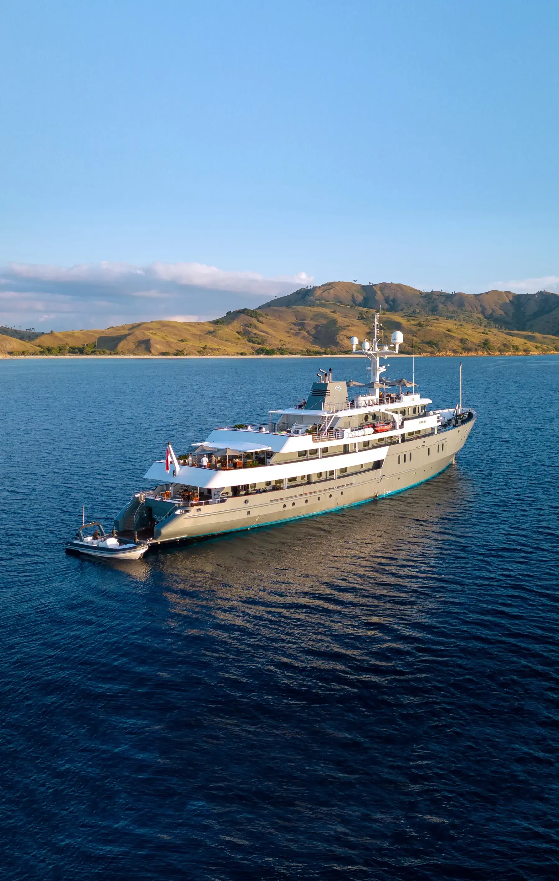 Aqua Blu at anchor off the dry hills of Komodo, her tender alongside