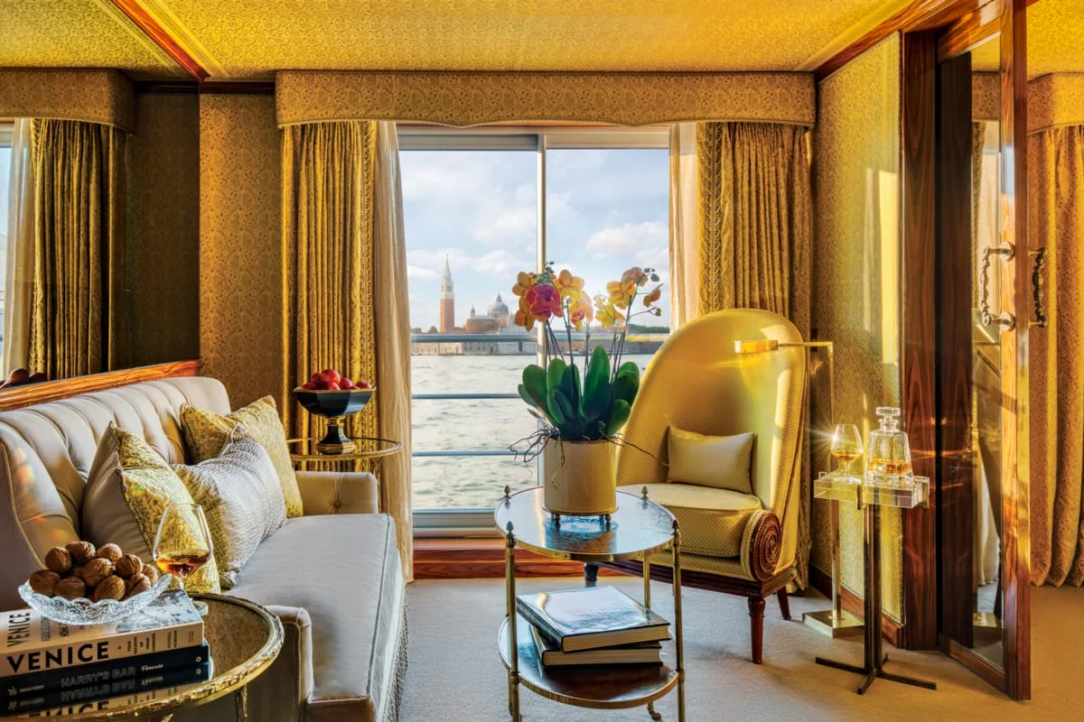 A suite sitting room aboard a Uniworld ship in Venice, gold silk walls and San Giorgio Maggiore through the window